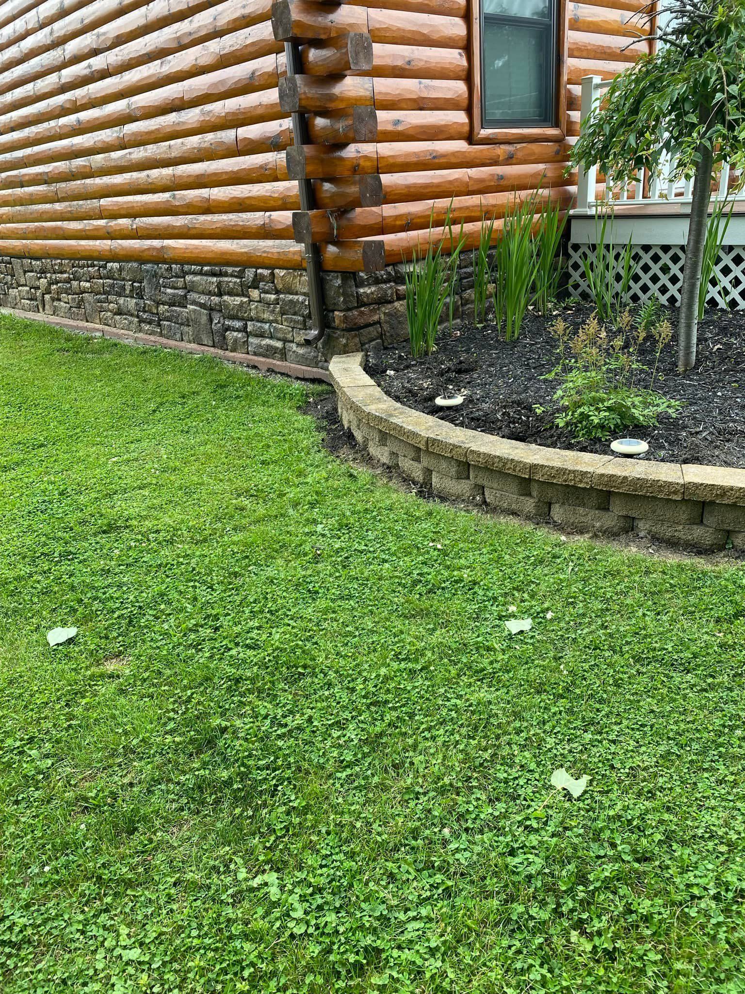 A log cabin with a lush green lawn in front of it.