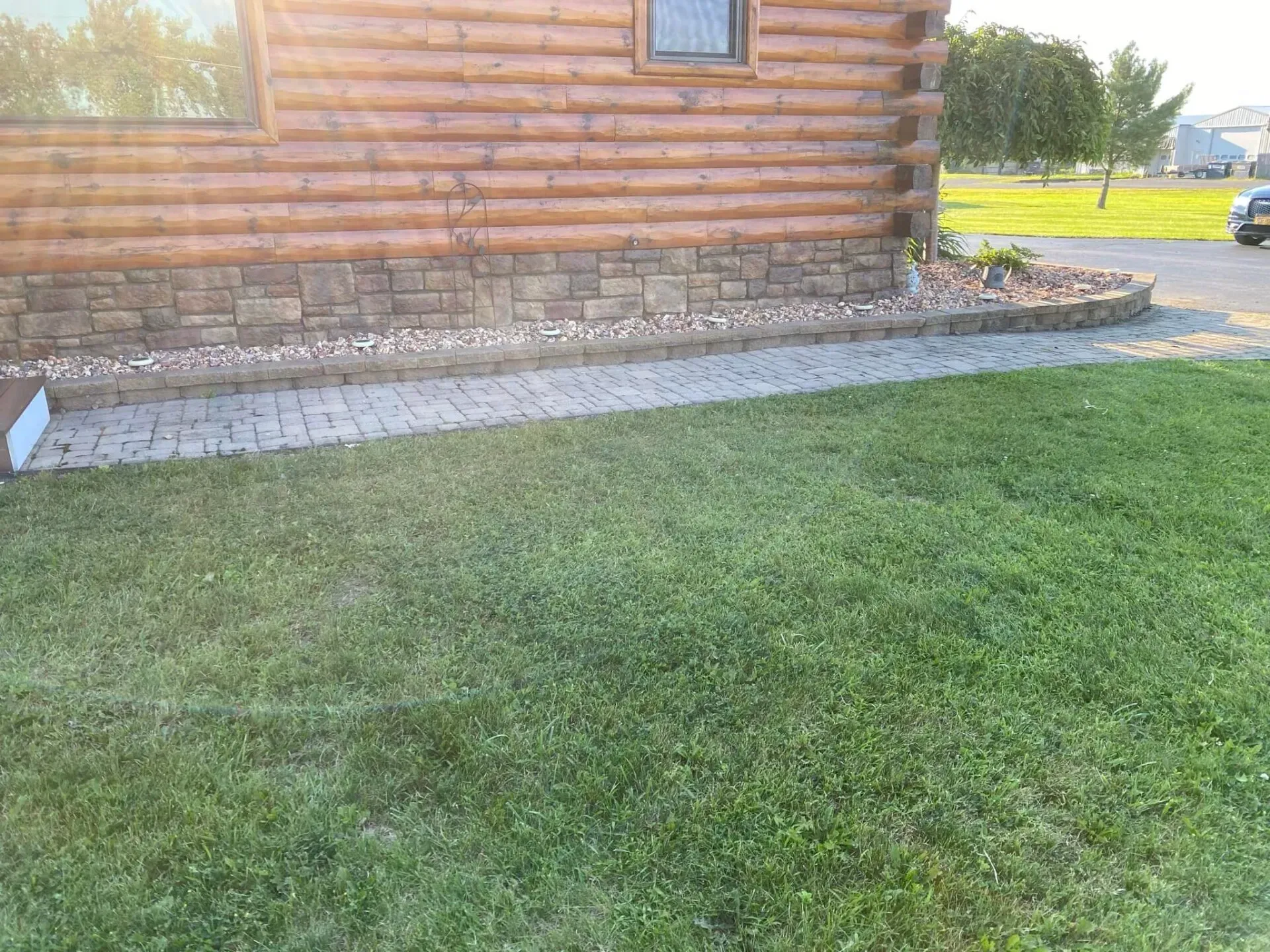 A log cabin with a lush green lawn in front of it.