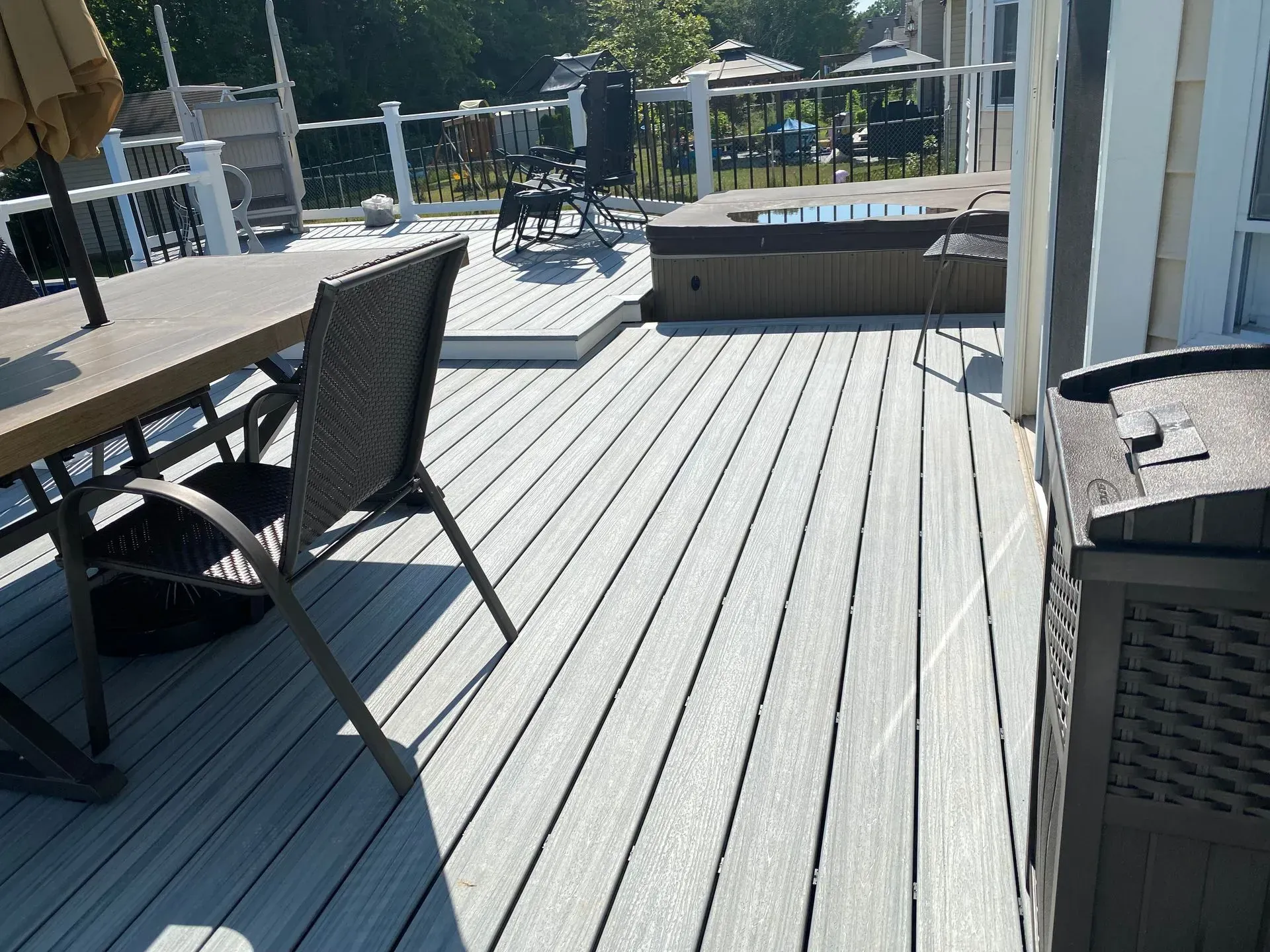 A deck with a table and chairs and a hot tub.