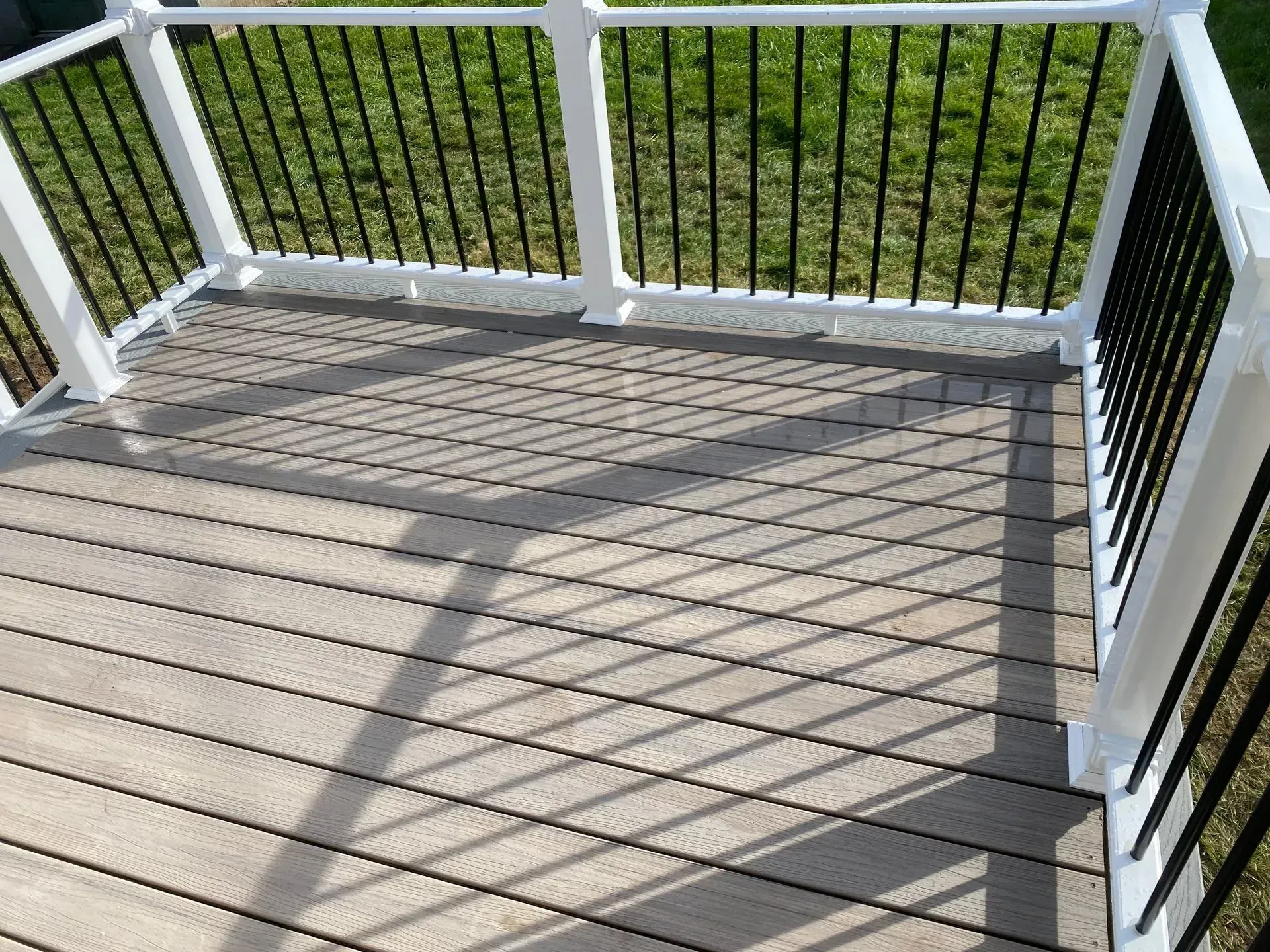 A wooden deck with a white railing and a black railing.
