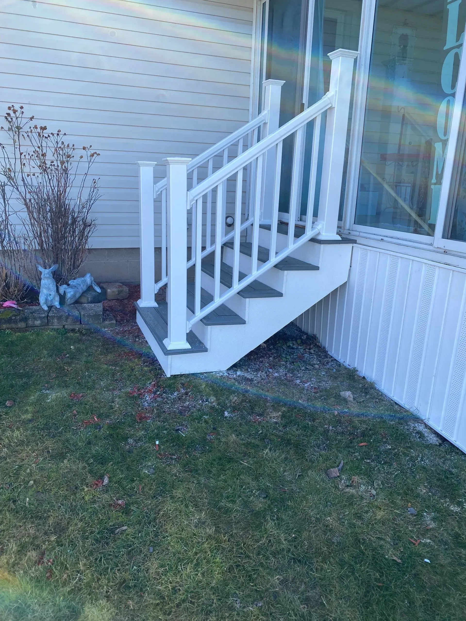 A set of stairs leading up to a porch with a white railing.