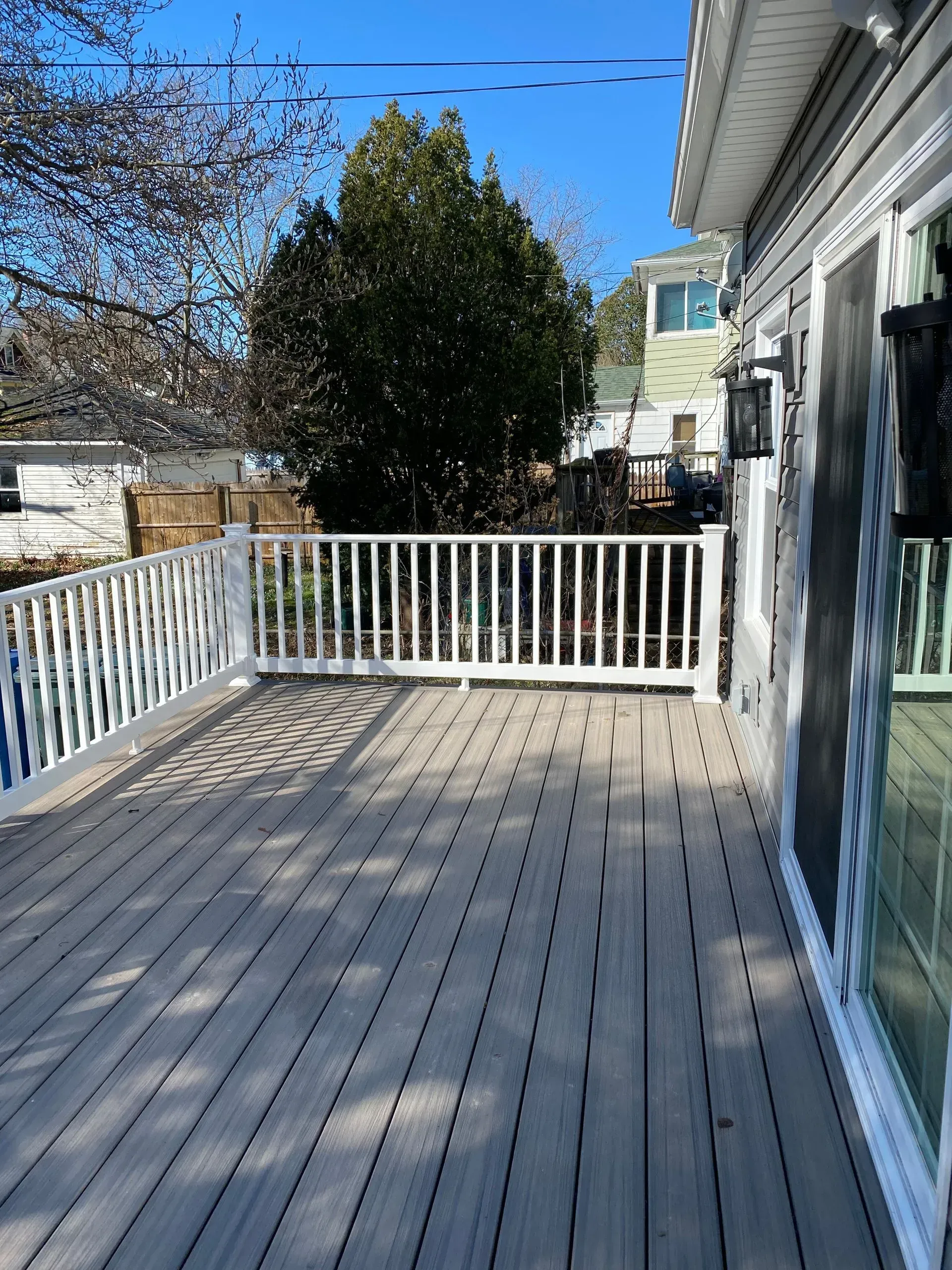 A large deck with a white railing and sliding glass doors.