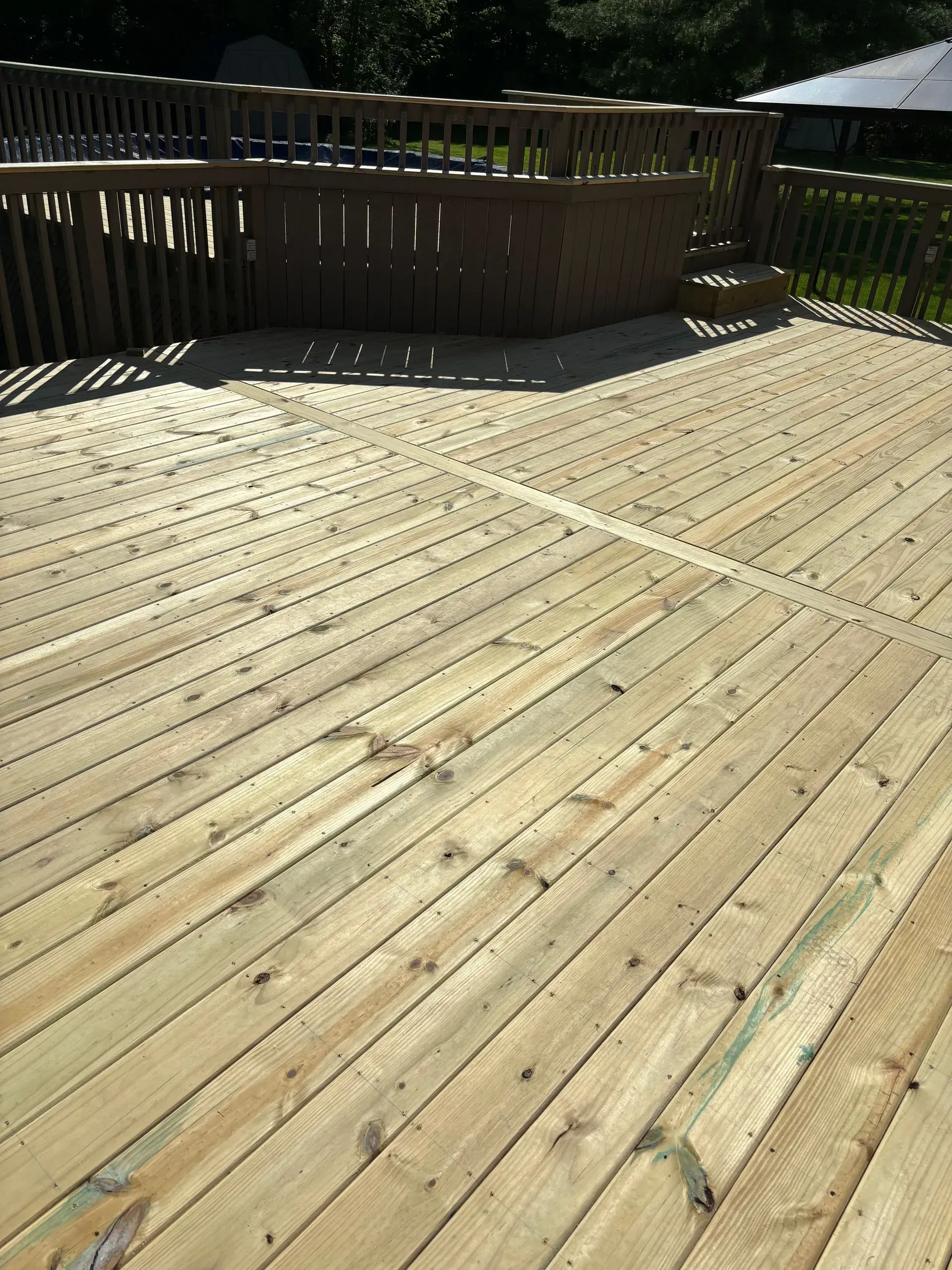 A large wooden deck with a railing and stairs