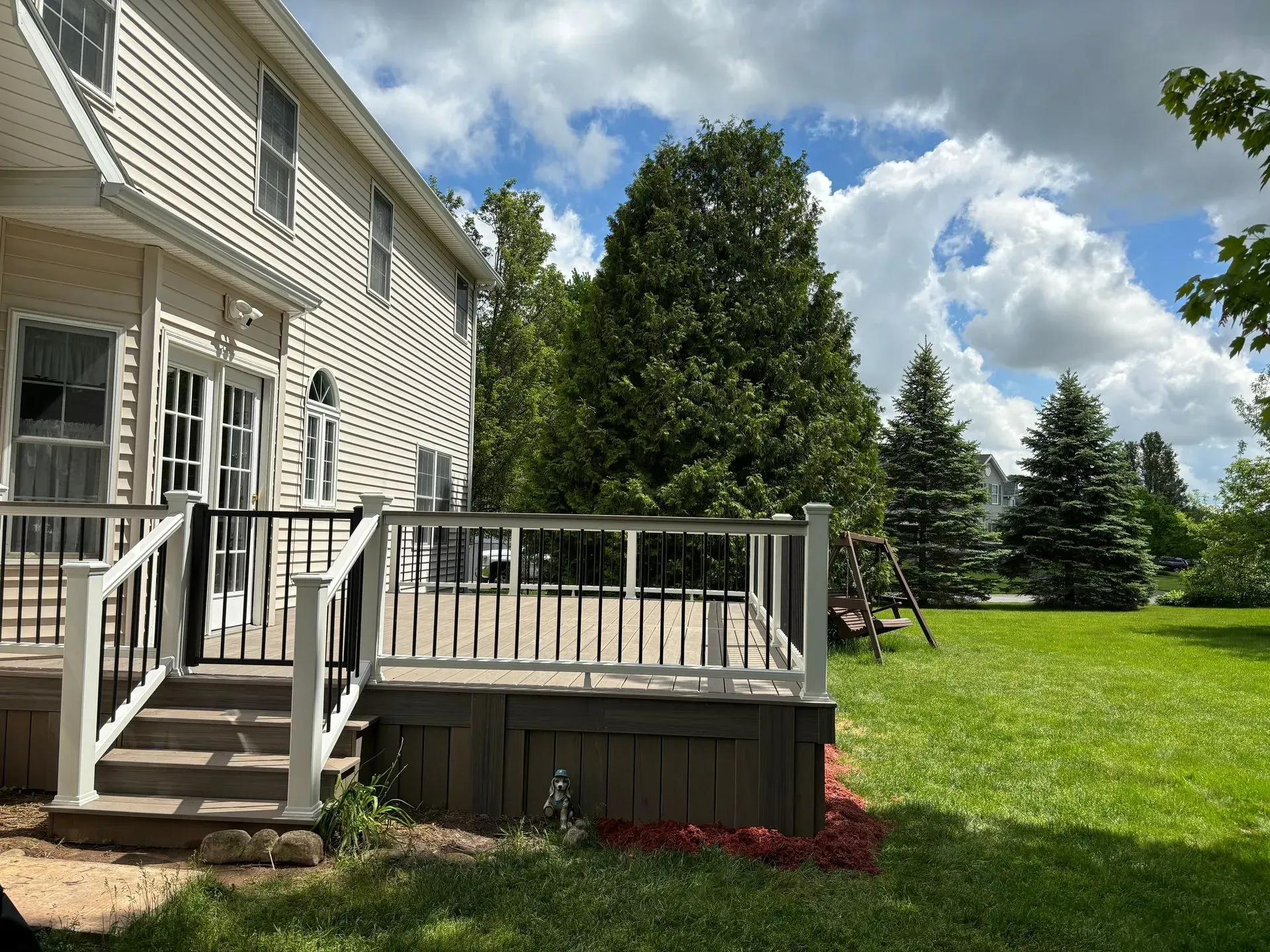 There is a large deck in the backyard of a house.