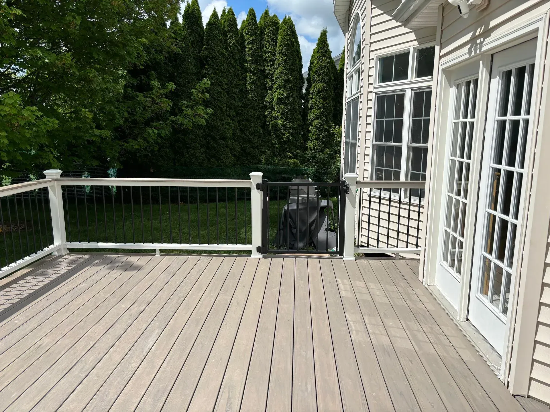 A large deck with a white railing and sliding glass doors.
