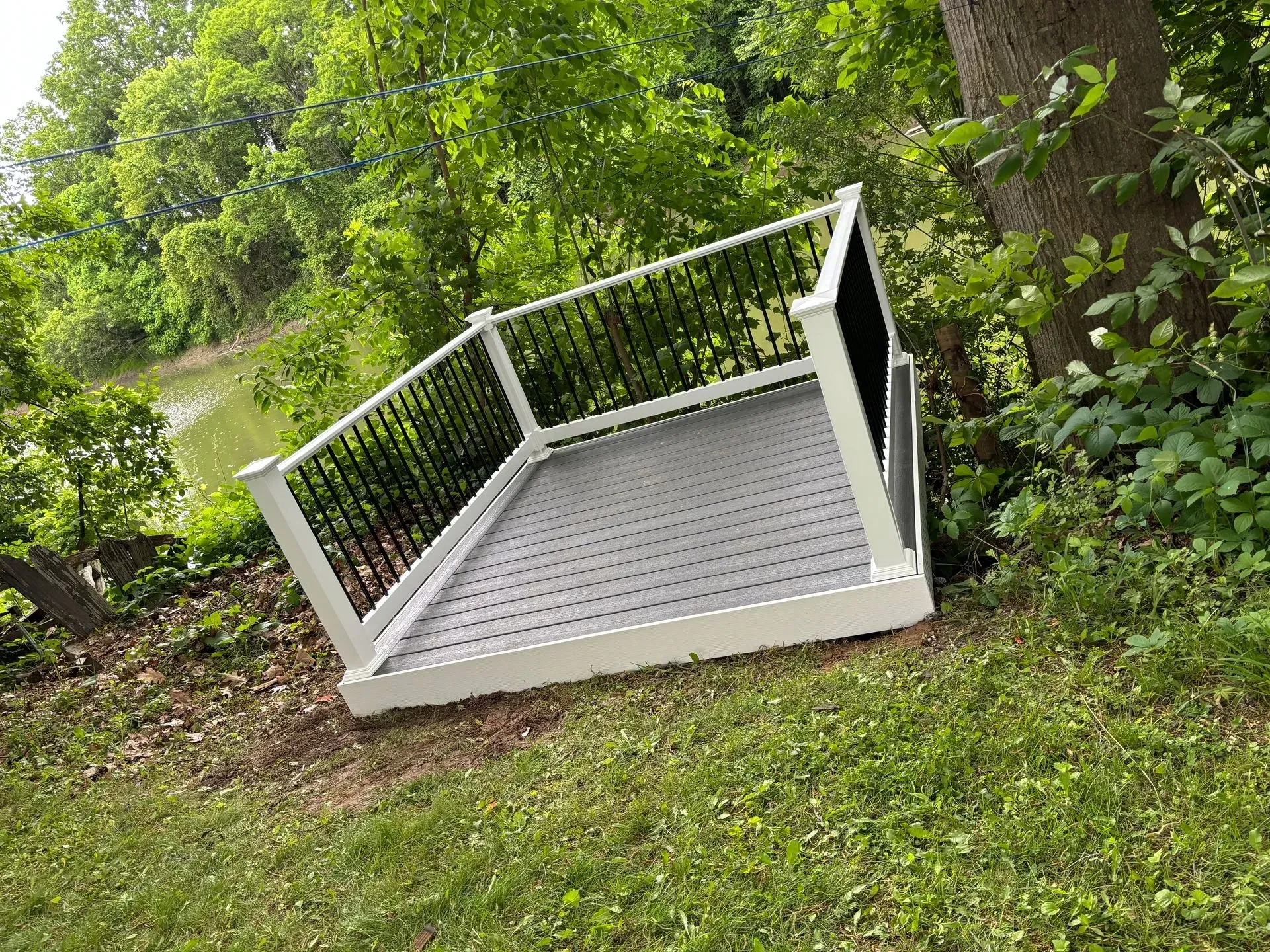 A white deck with a black railing is sitting on top of a lush green field.