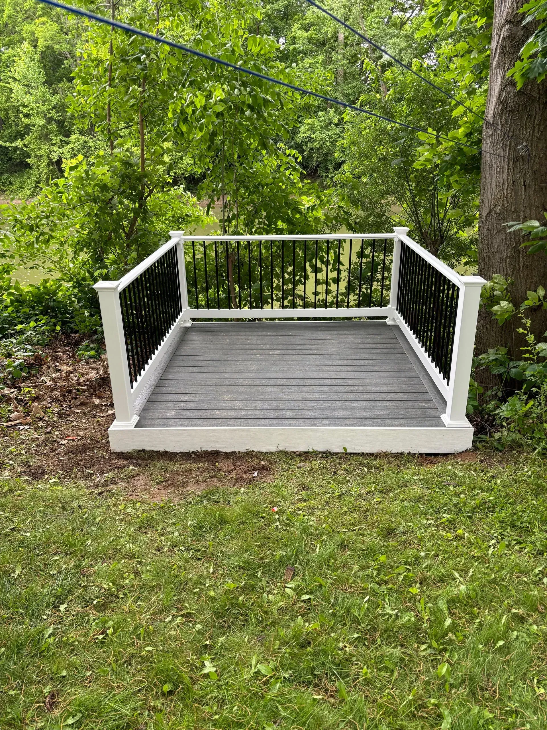 A small deck with a white railing is sitting in the middle of a lush green field.
