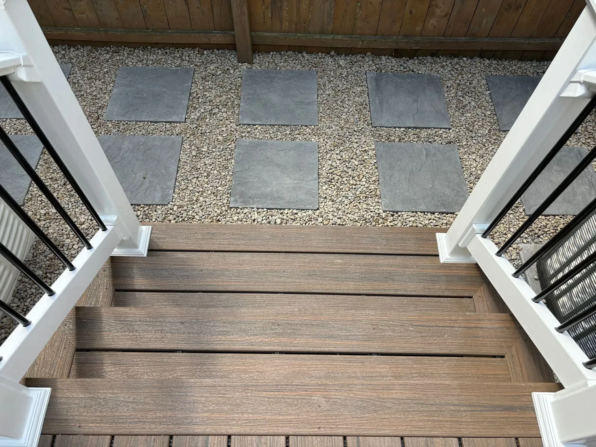 A wooden deck with stairs and a fence in the background