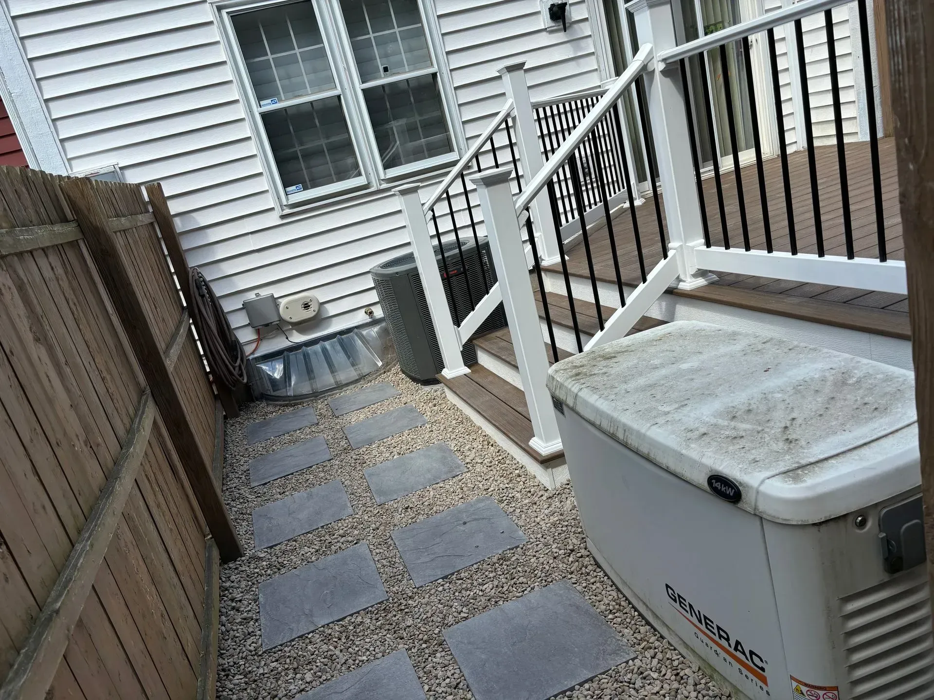 A generator is sitting on the sidewalk in front of a house.