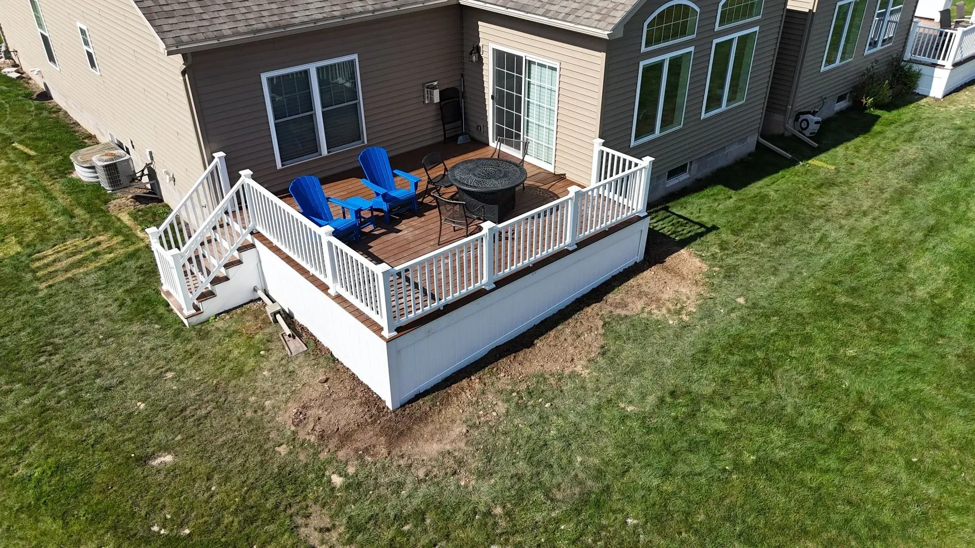 An aerial view of a deck with chairs and a table in front of a house.