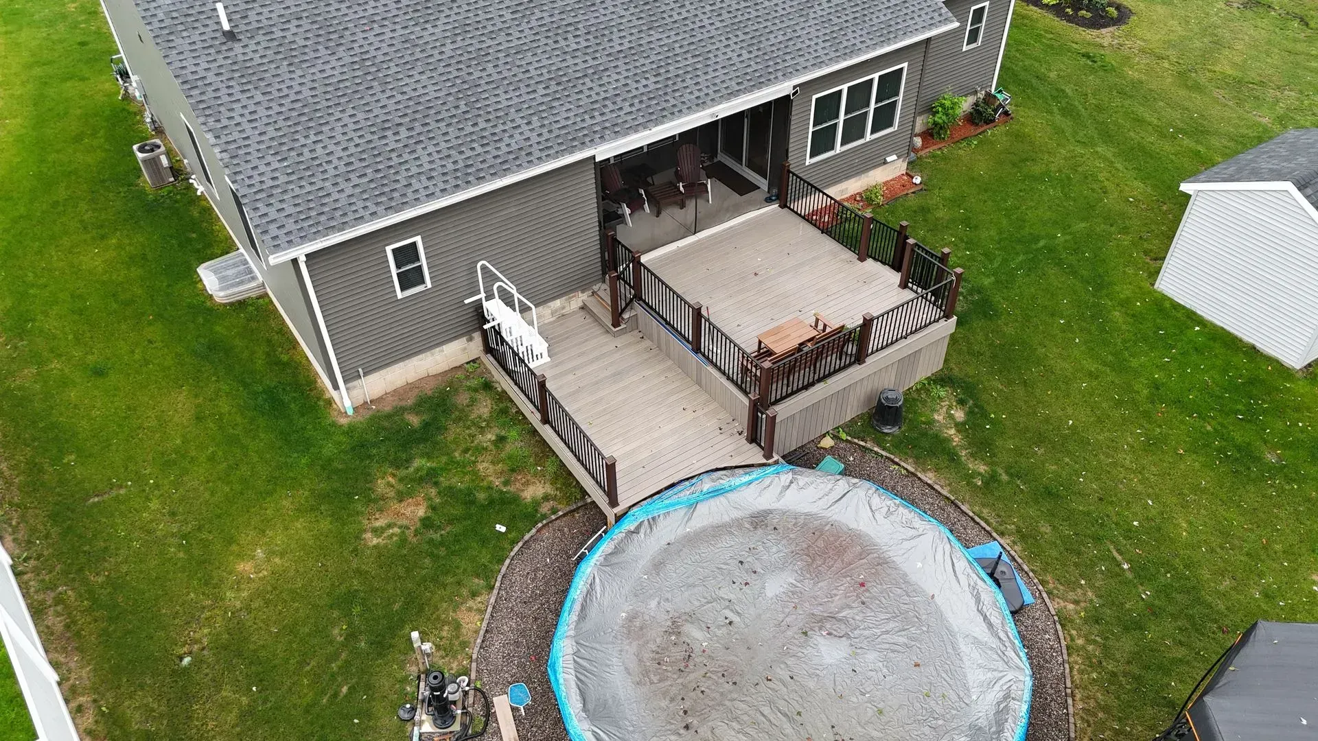 An aerial view of a house with a trampoline in the backyard.