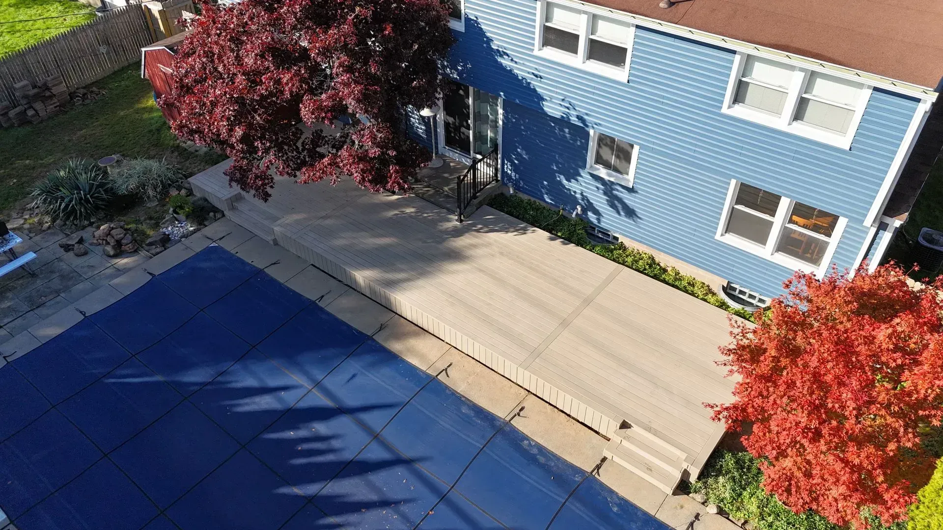 An aerial view of a blue house with a swimming pool in front of it.