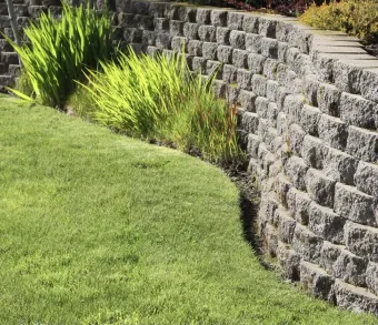 A stone wall surrounds a lush green lawn.