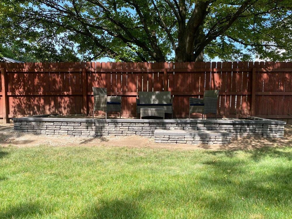 A backyard with a stone wall and a wooden fence.