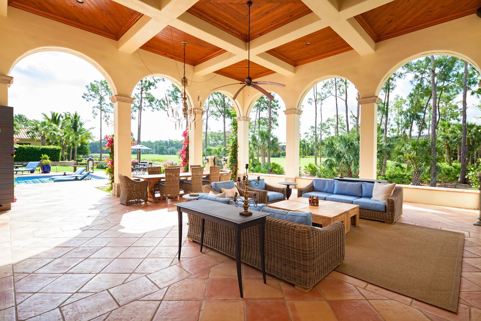 A patio with a couch , table , chairs and a ceiling fan