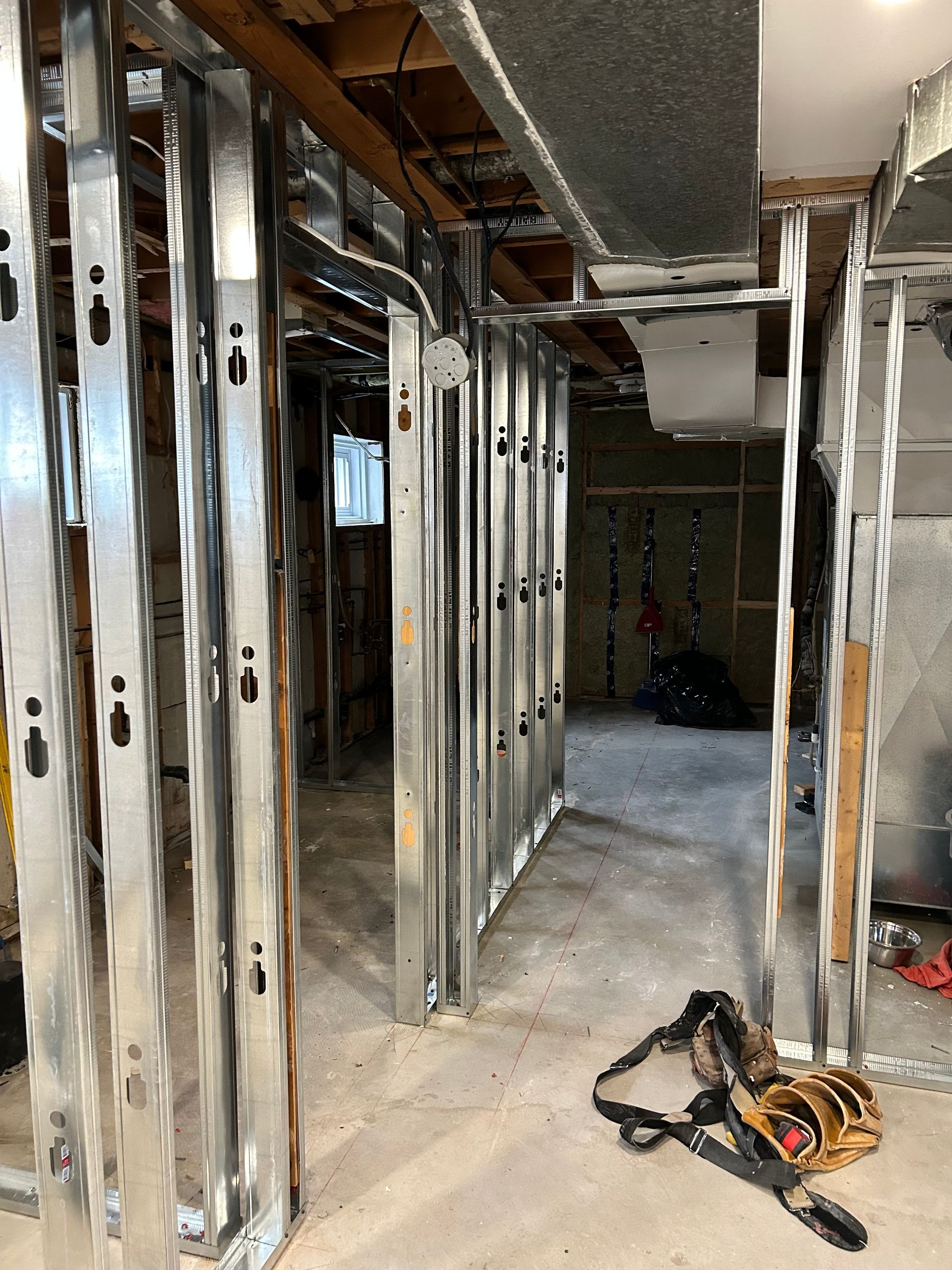 Une pièce avec beaucoup de cadres métalliques et un sac à outils sur le sol.