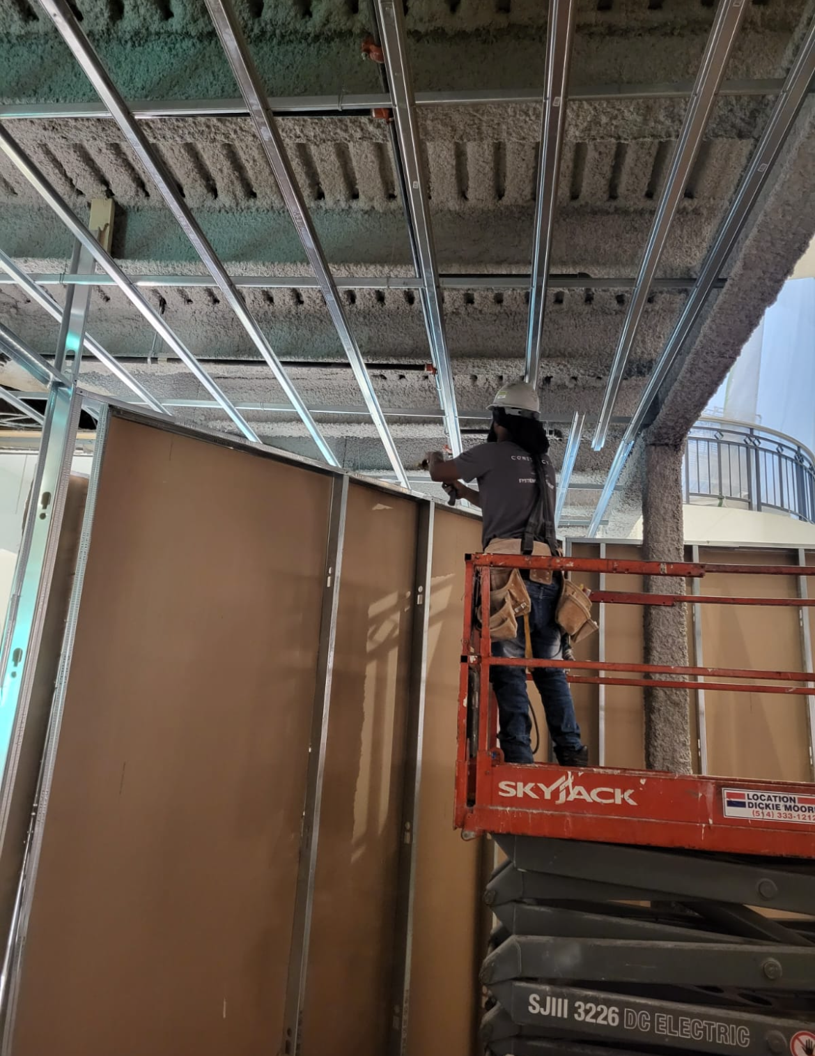 Un homme est debout sur un ascenseur et travaille sur un plafond.
