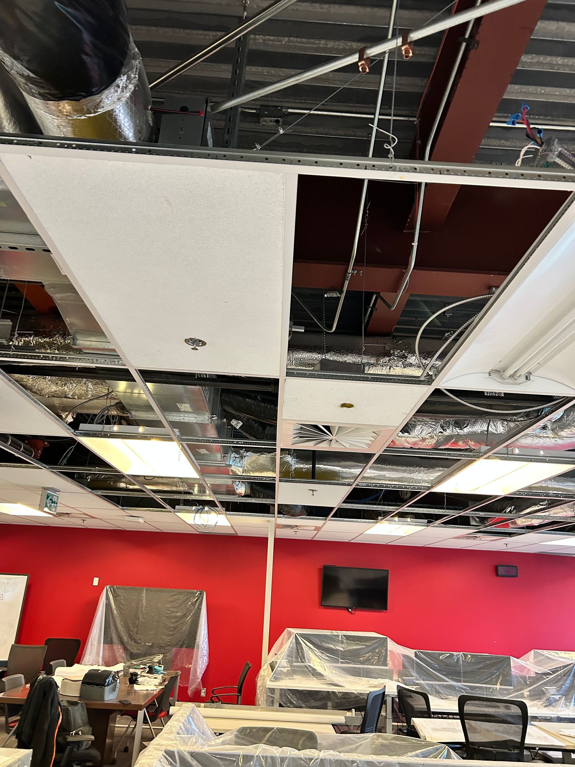 Une pièce avec un plafond manquant et un mur rouge.