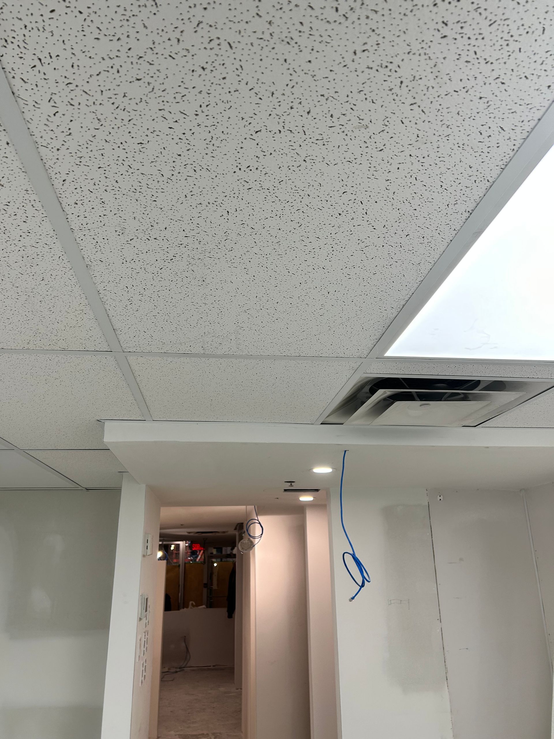 Un couloir avec un plafond carrelé et une lumière