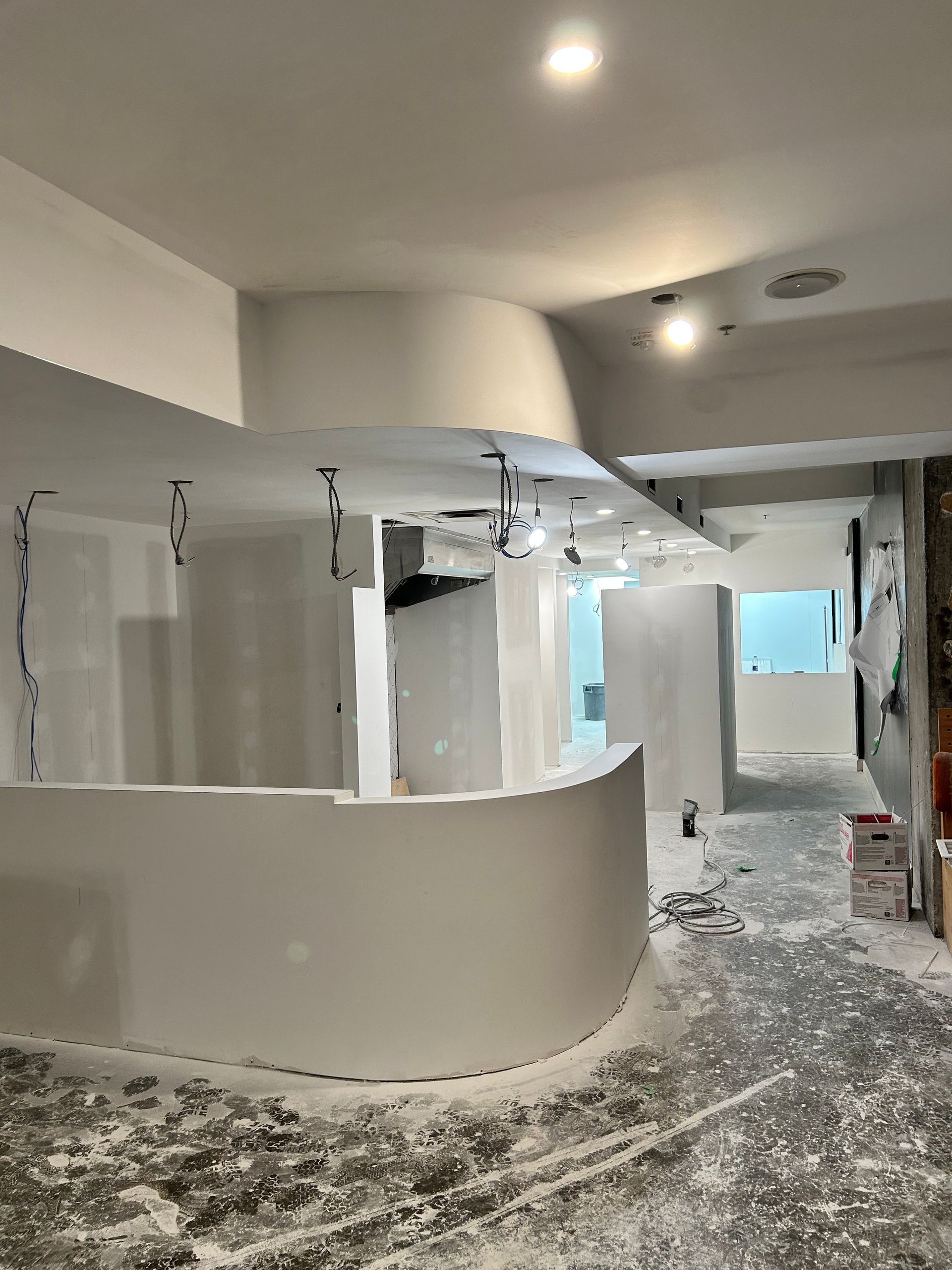 Une grande pièce avec un mur courbé et beaucoup de poussière sur le sol.