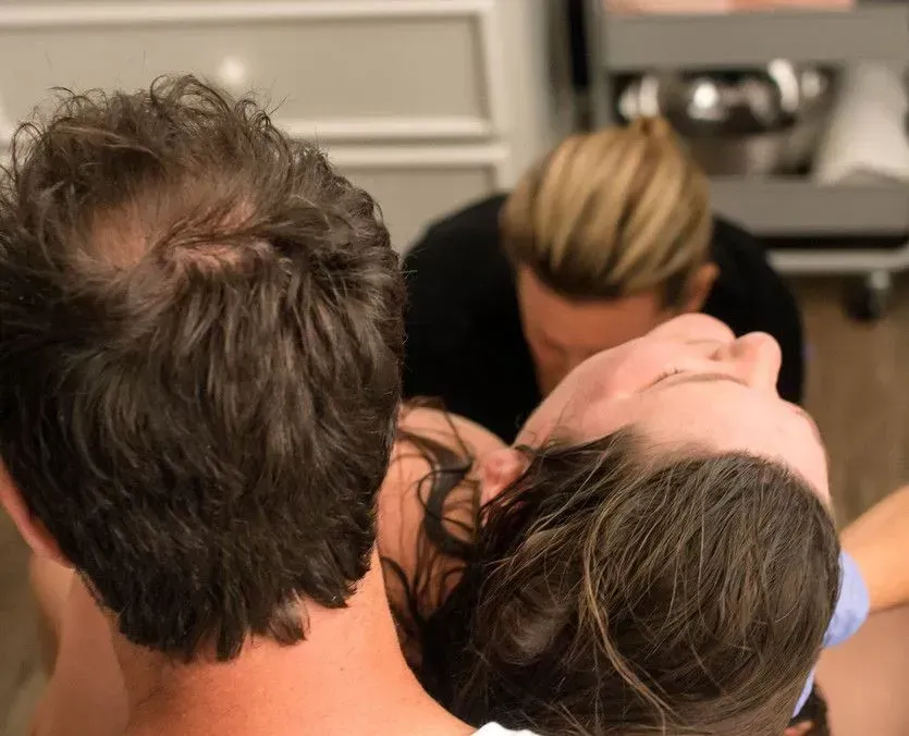Man and woman with blond nurse, possibly in medical setting; woman looking up.