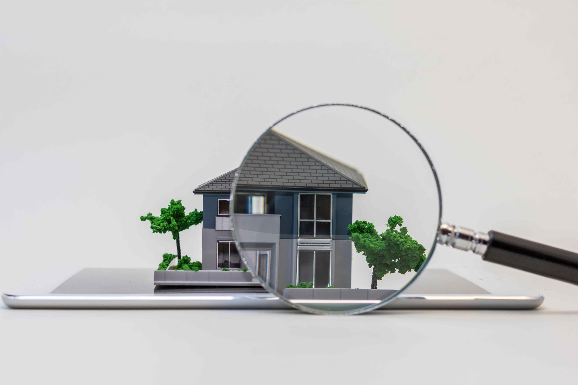 small model house with a magnifying glass in front