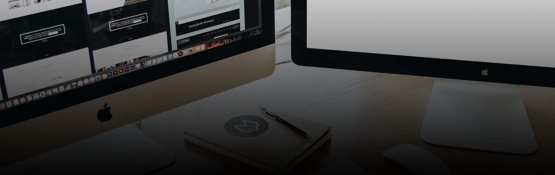 A computer monitor is sitting on a desk next to a book.