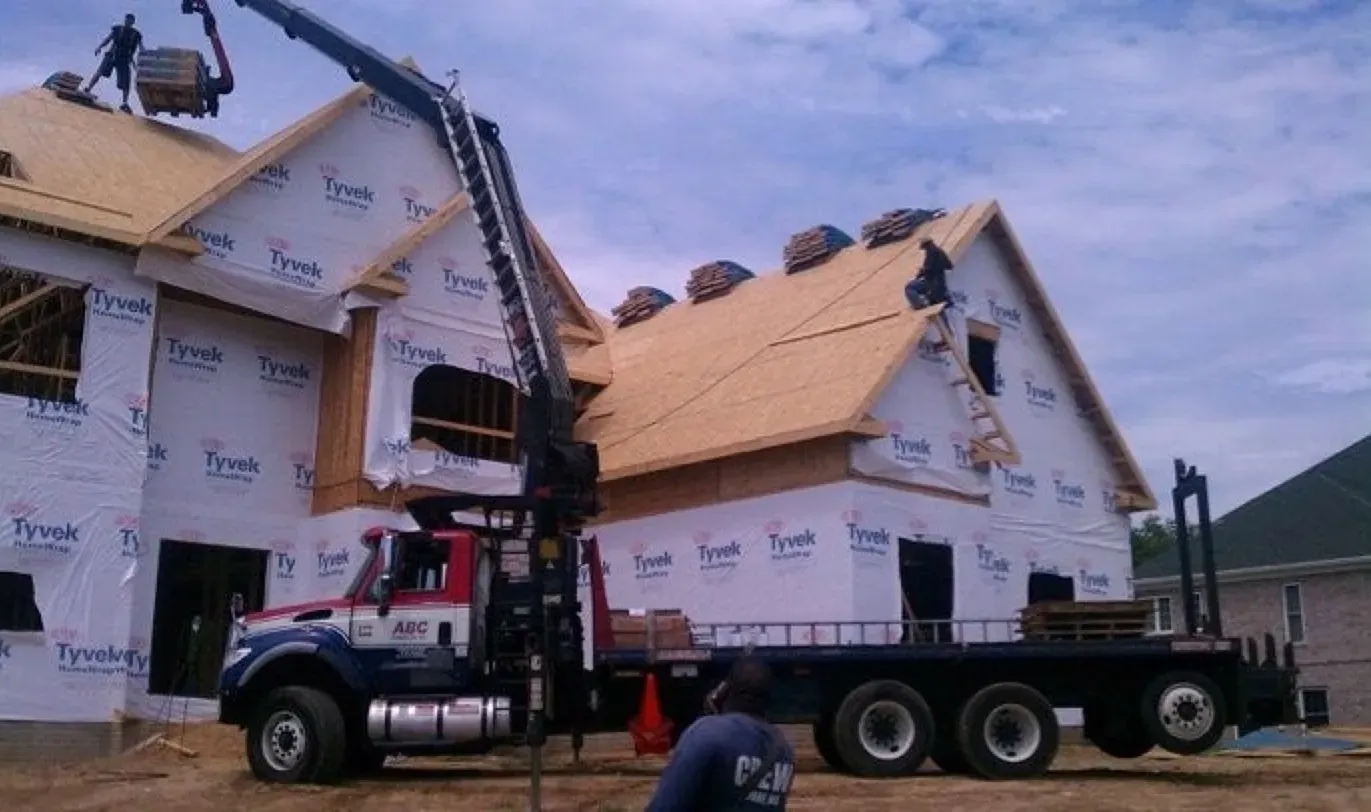 A construction truck is parked in front of a house under construction