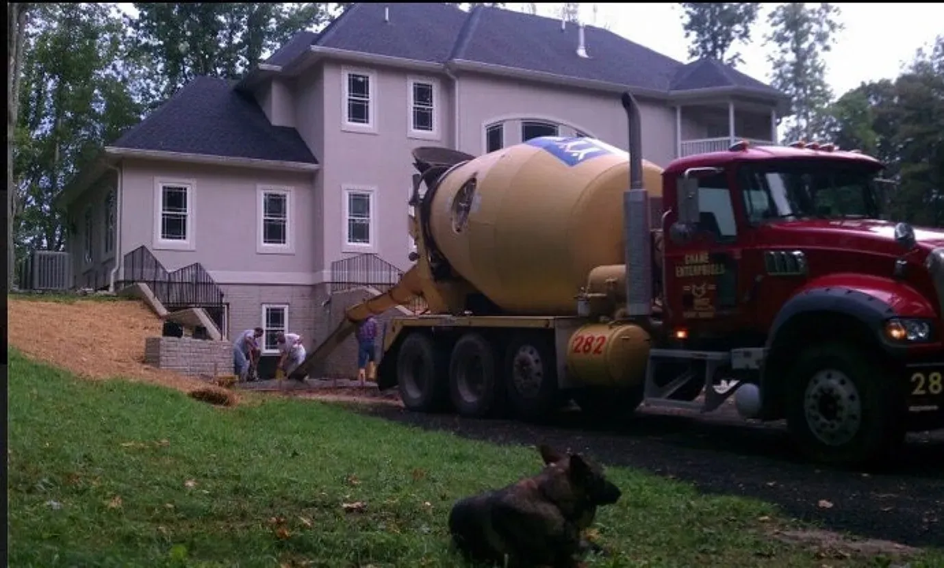 A concrete mixer truck is parked in front of a house