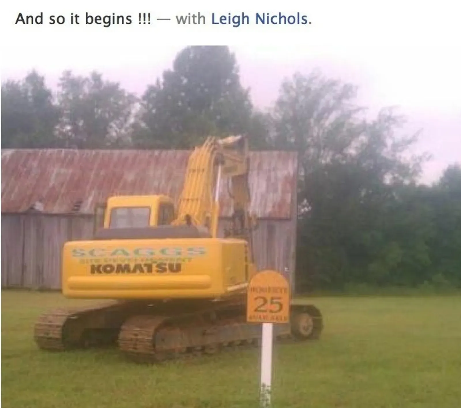 A komatsu excavator is parked in front of a barn