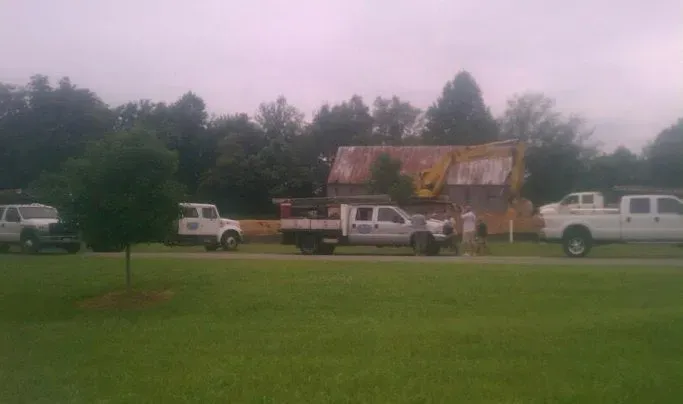 A row of white trucks are parked in front of a house under construction.