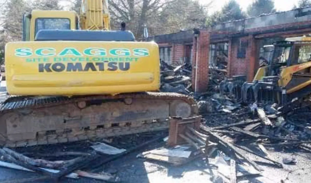A yellow komatsu excavator is demolishing a building.