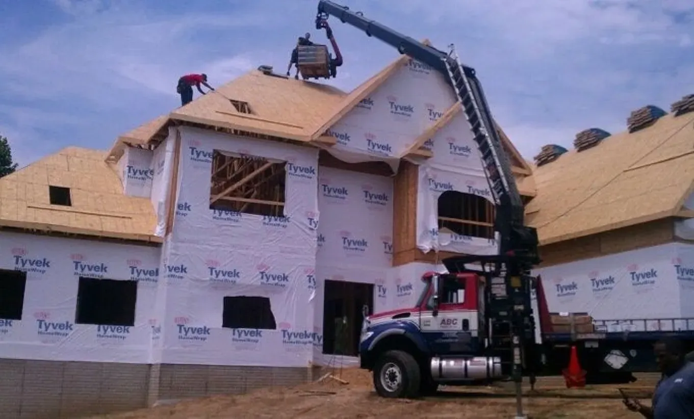 A truck is parked in front of a house that is being built