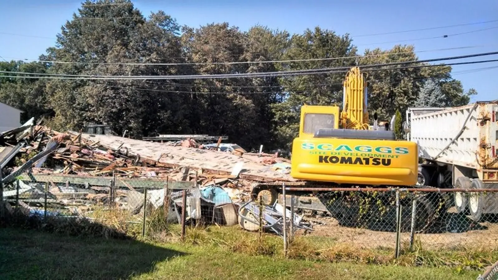 A yellow komatsu excavator is being used to demolish a building