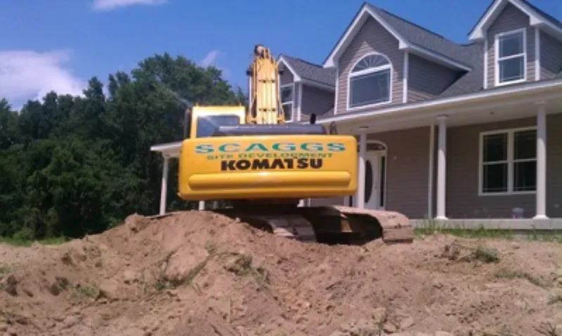 A komatsu excavator sits in front of a house as it excavates water lines.
