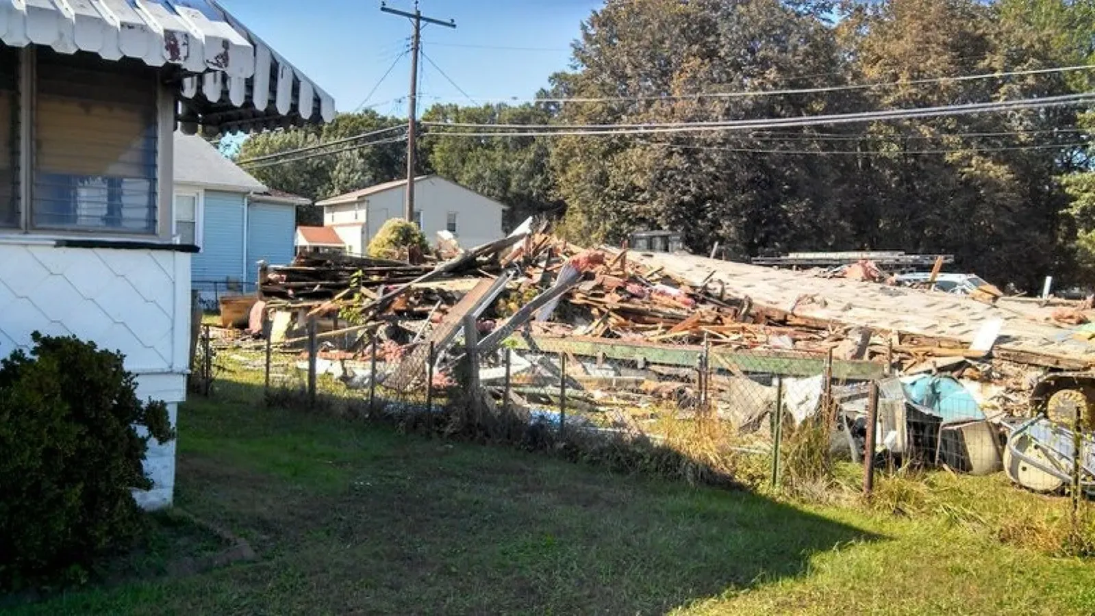 A house is being demolished in the middle of a grassy field.