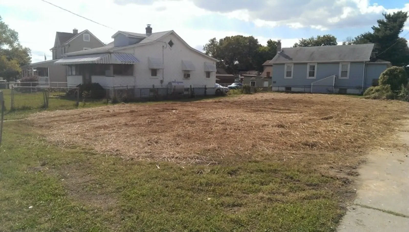 A house with a lot of grass in front of it next to a buildable lot.
