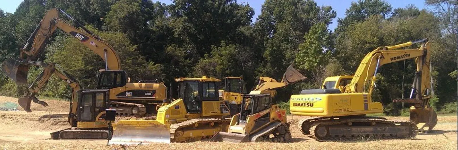 A group of construction vehicles are parked in a field.