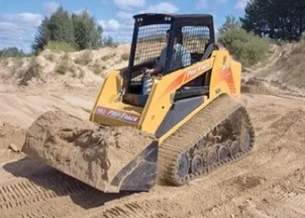 A yellow bulldozer is driving down a dirt road