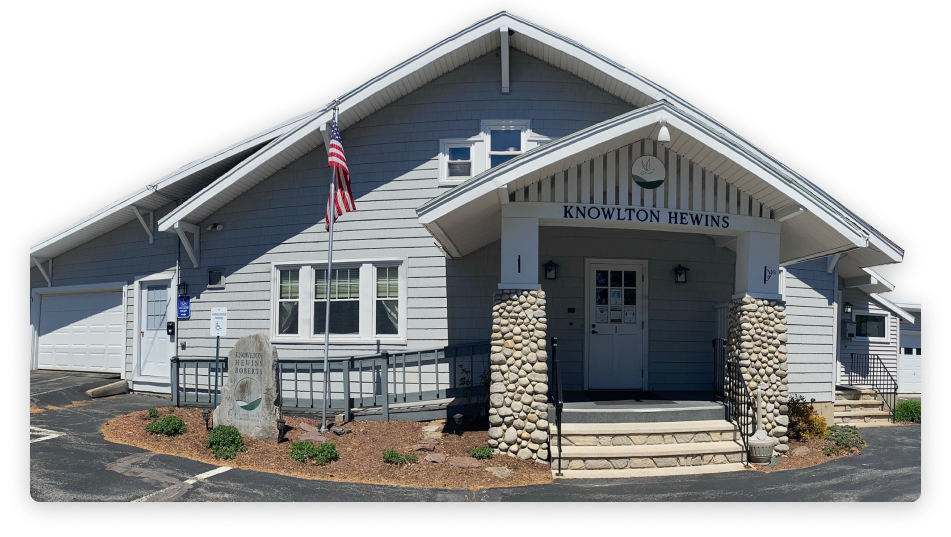 Gray building with white trim, stone columns, American flag, and sign reading