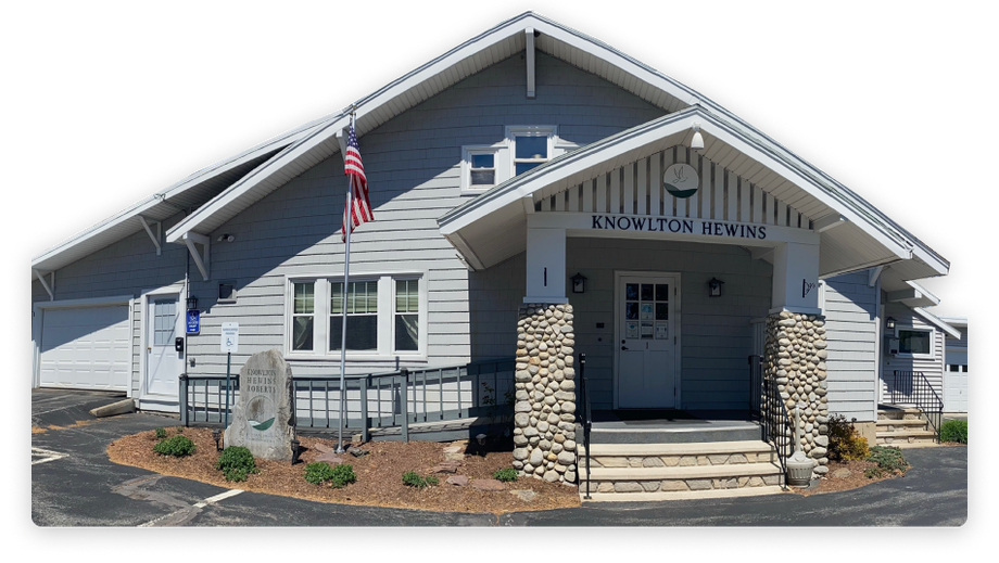 Grey building with stone columns, stairs, and American flag. 