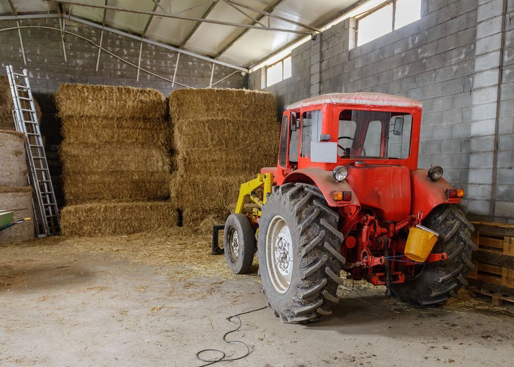 A Red Tractor is Parked in a Barn Filled With Hay Bales — LJE MechanicaI Gilgandra, NSW
