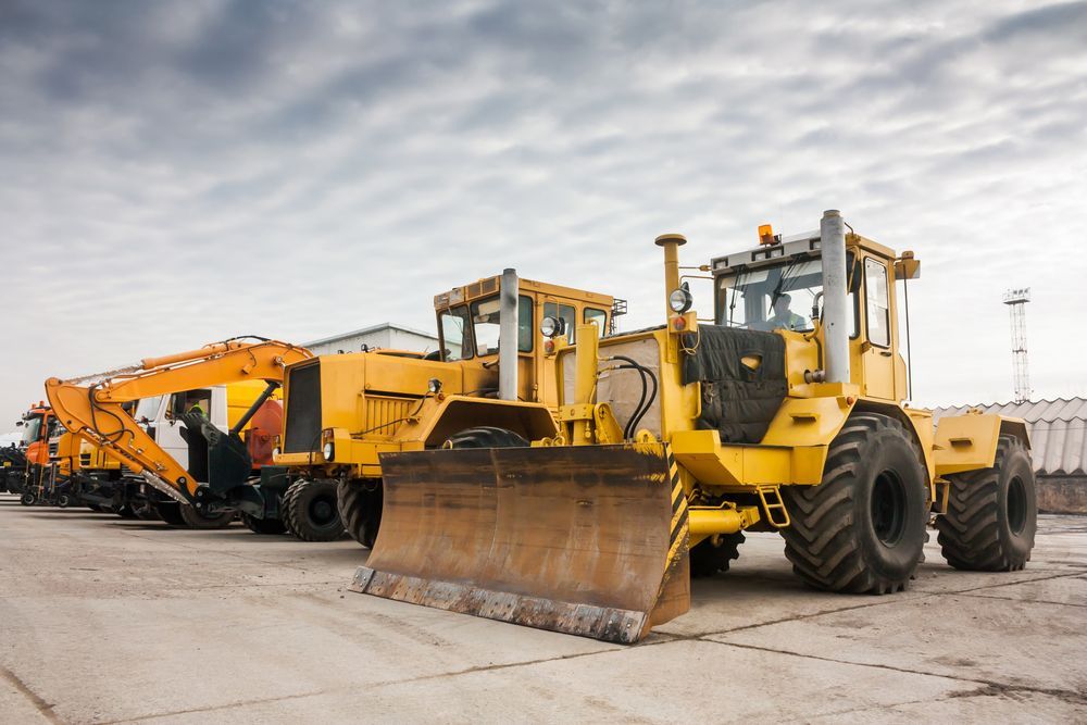 A Row of Yellow Construction Vehicles Are Parked in a Parking Lot — LJE MechanicaI Gilgandra, NSW