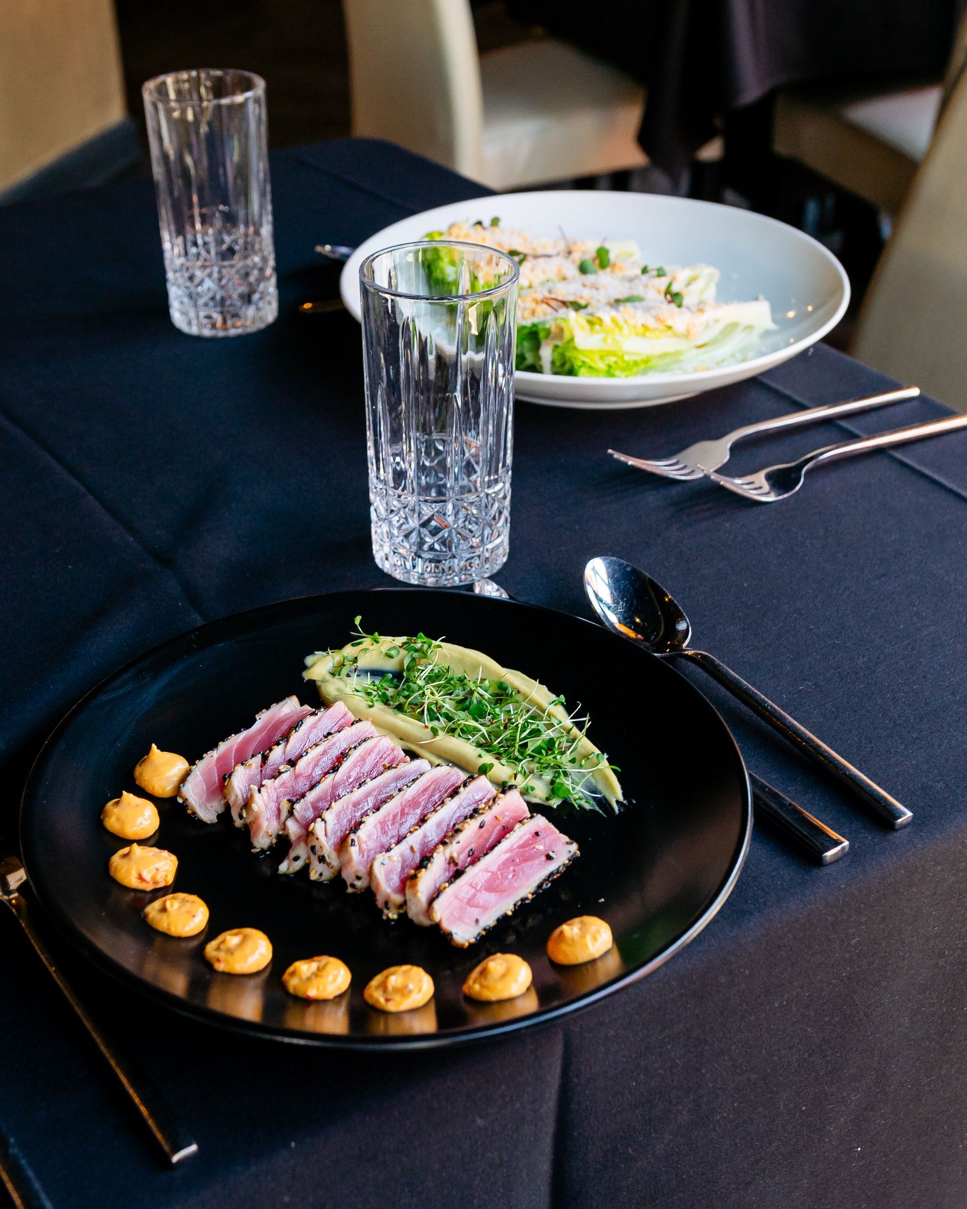 A black plate topped with meat and vegetables on a table.