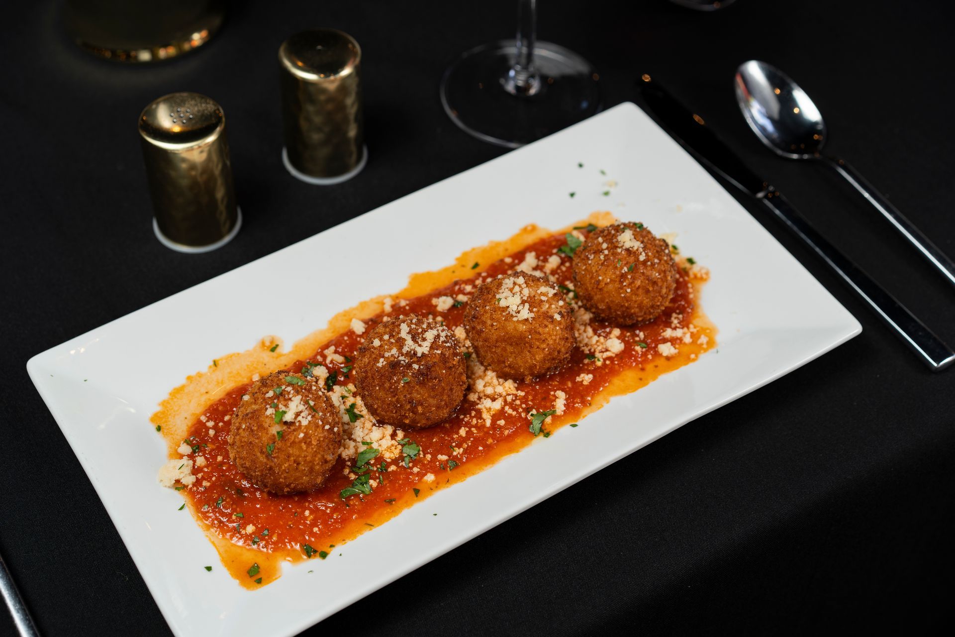 A white plate topped with meatballs and sauce on a table