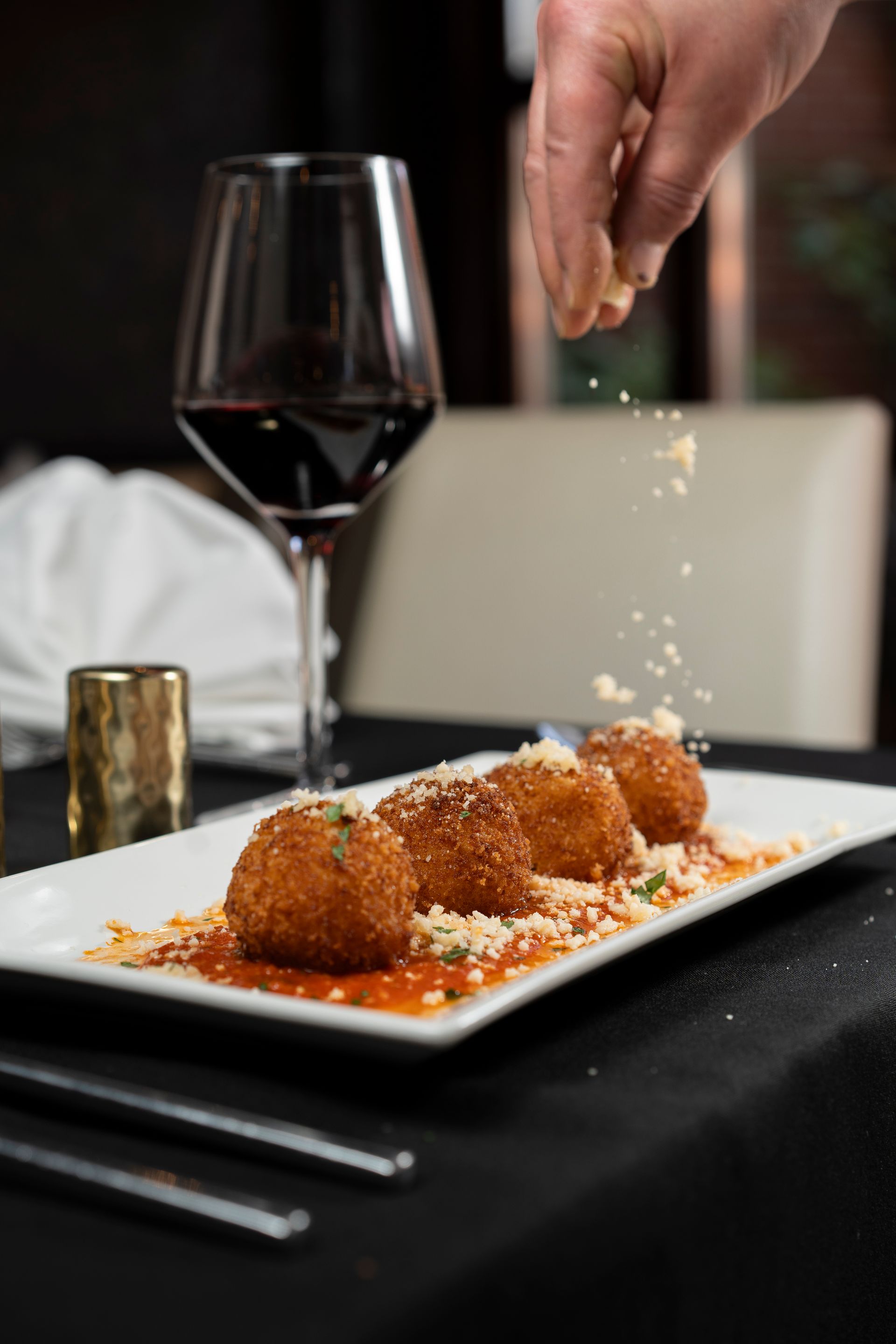A plate of food with a glass of wine in the background