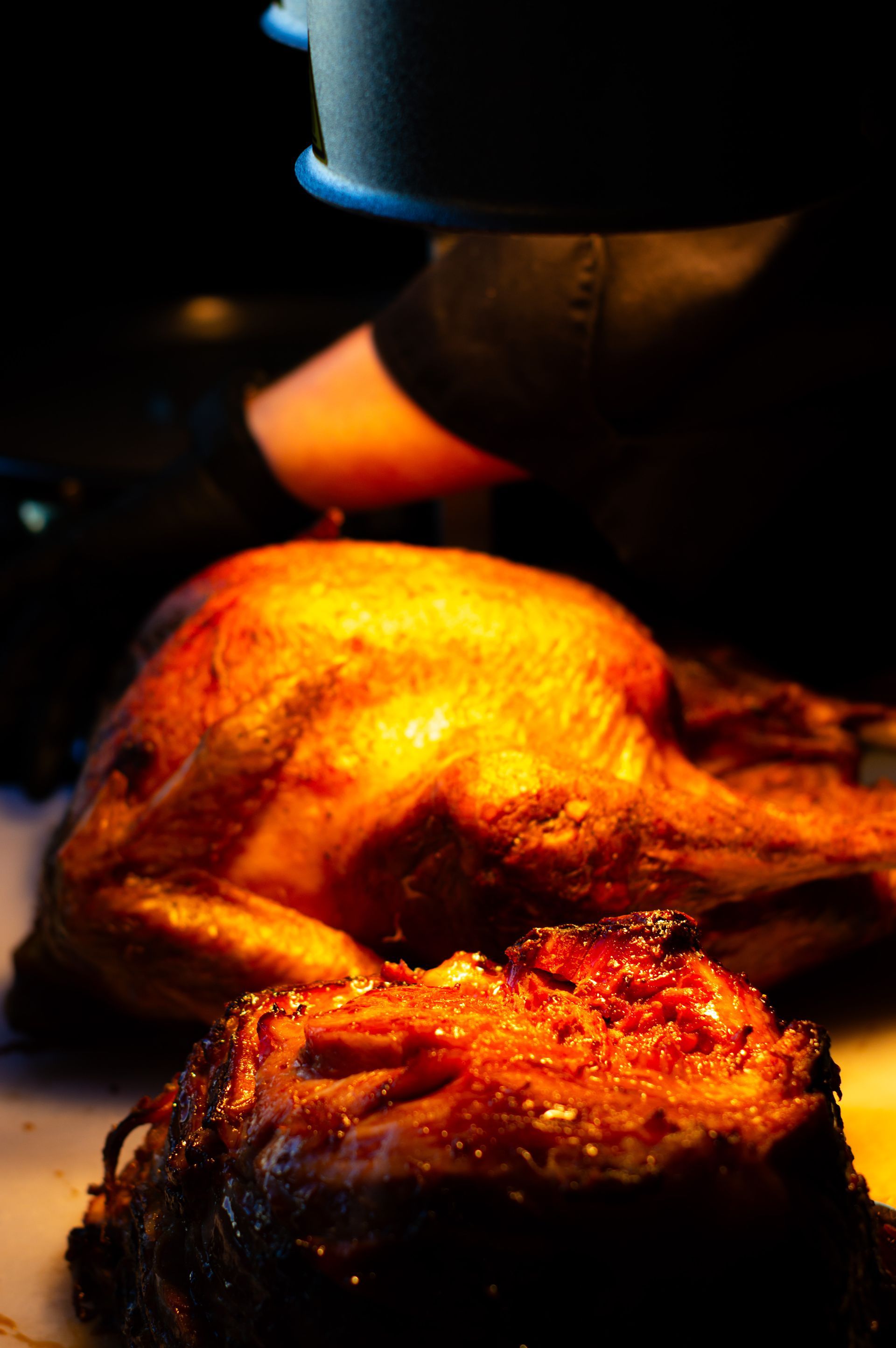 A close up of a roasted chicken and a piece of meat on a table.