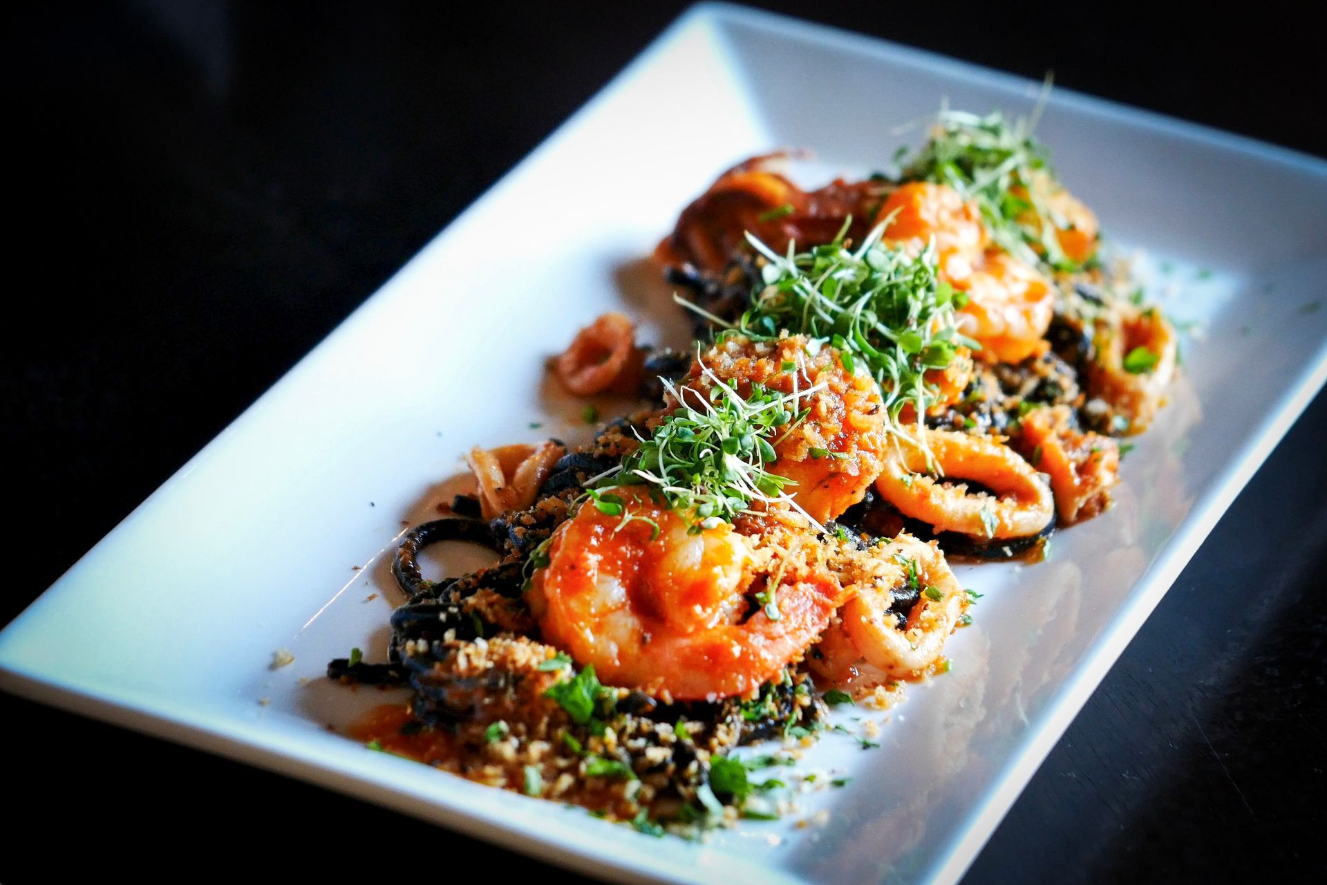 A white plate topped with shrimp and squid on a table