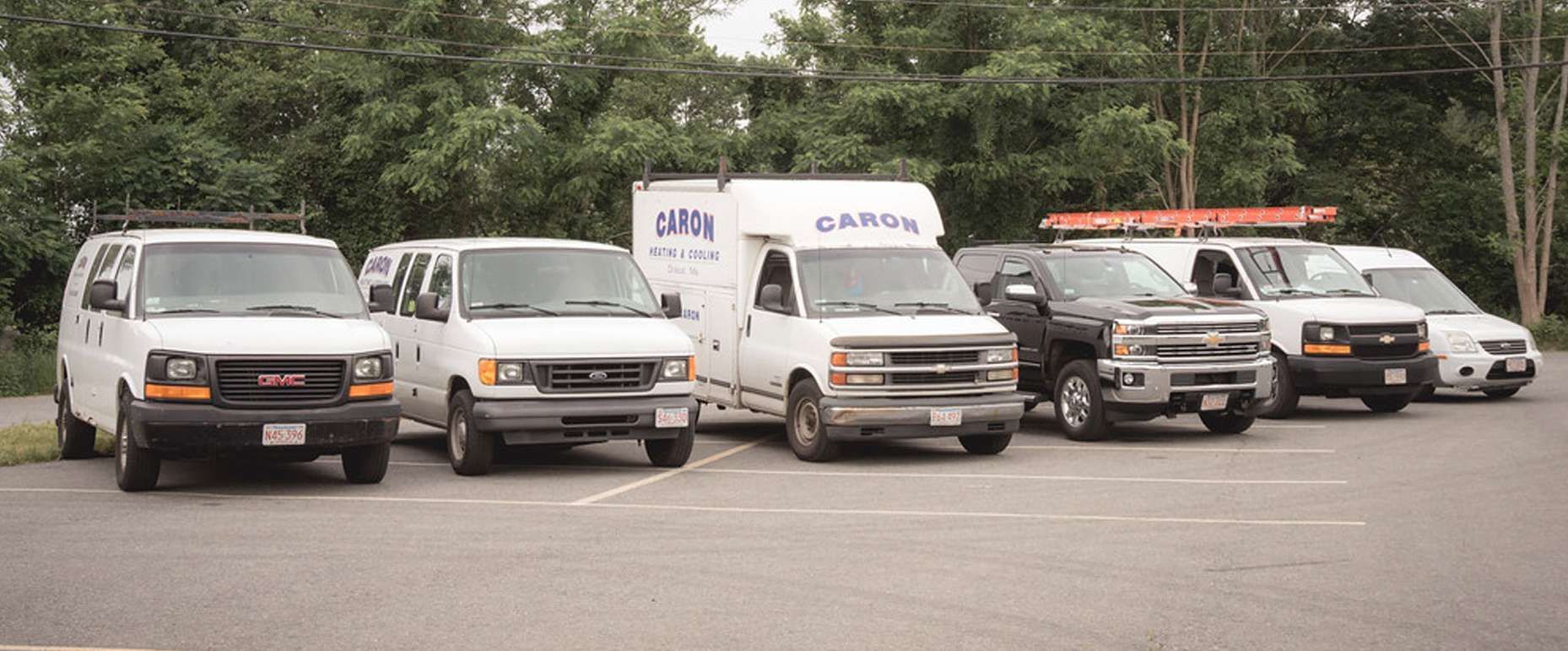 A row of vans are parked in a parking lot