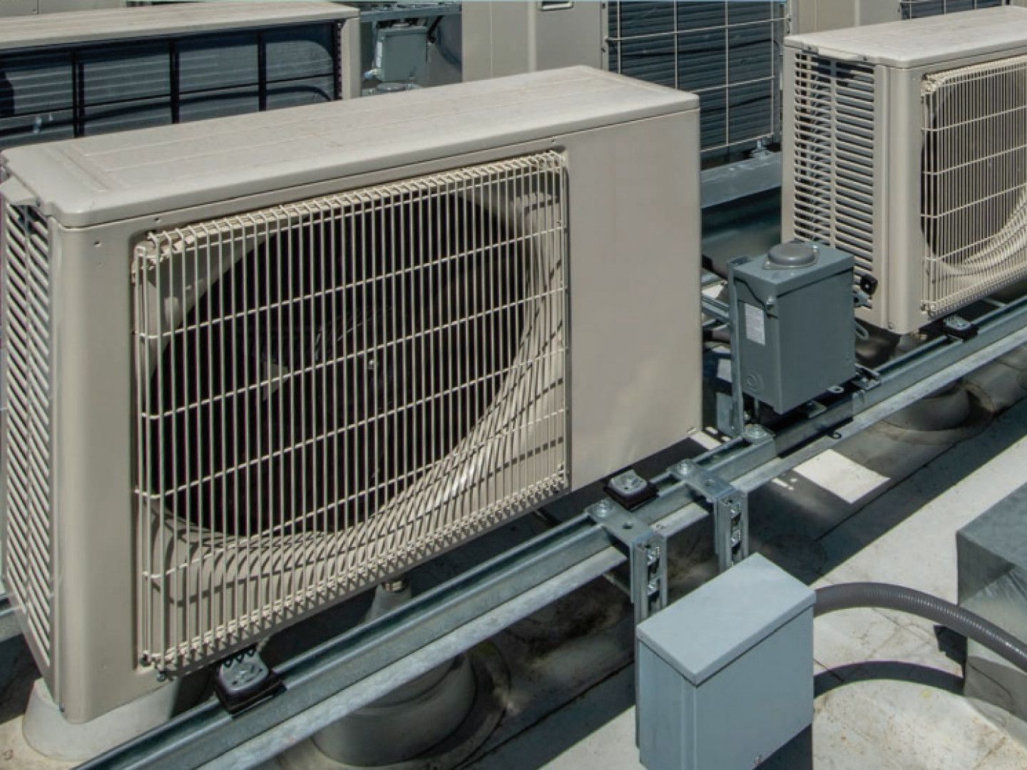 A row of air conditioners are sitting on top of a building.